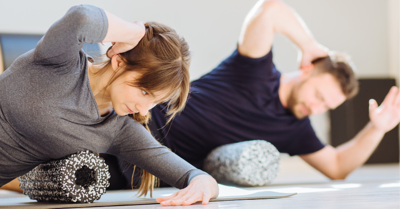 Dvaja ľudia používajú foam roller na cvičenie na podložke