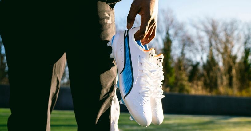 Osoba drží futbalové kopačky na ihrisku