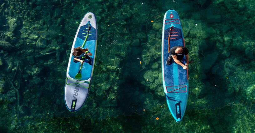 Dvaja ľudia pádlovali na paddleboardoch na pokojnej vode