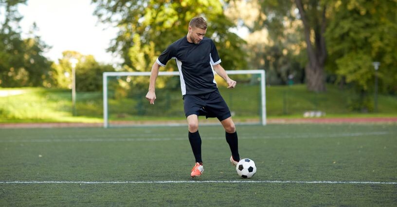 Hráč na futbalovom ihrisku pri bráne s loptou