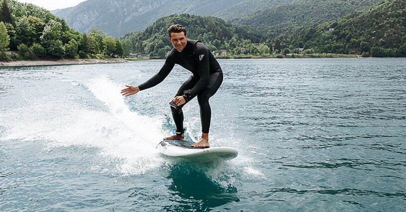 Muž jazdí na elektrickej surfovej doske na jazere
