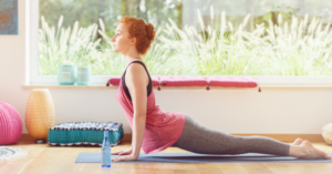 Osoba cvičí jogu na podložke pri okne s prírodným výhľadom