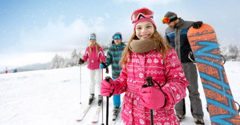 Dieťa so skupinou ľudí na lyžiach a snowboarde v zasneženej krajine