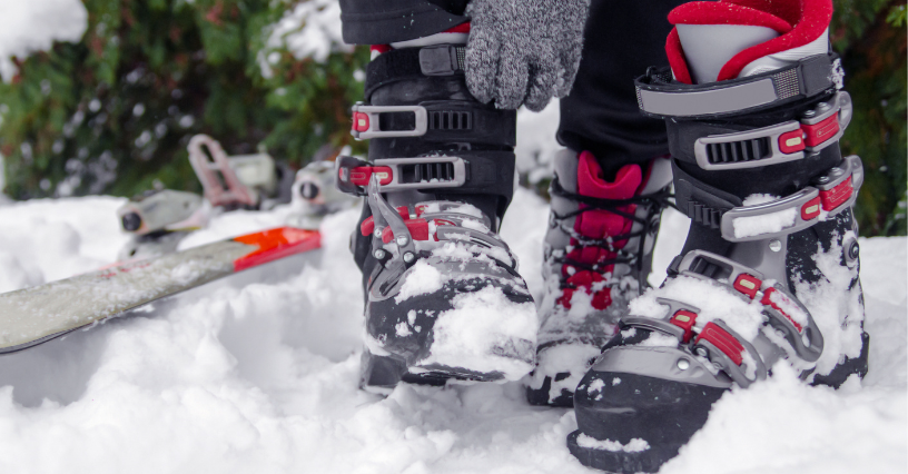 Osoba si nasadzuje lyžiarske topánky vedľa lyží na snehu