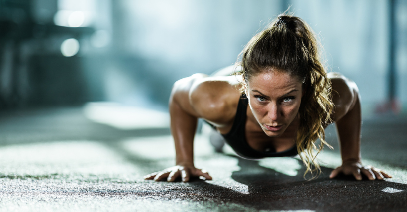 Žena cvičí kliky na podlahe v telocvični