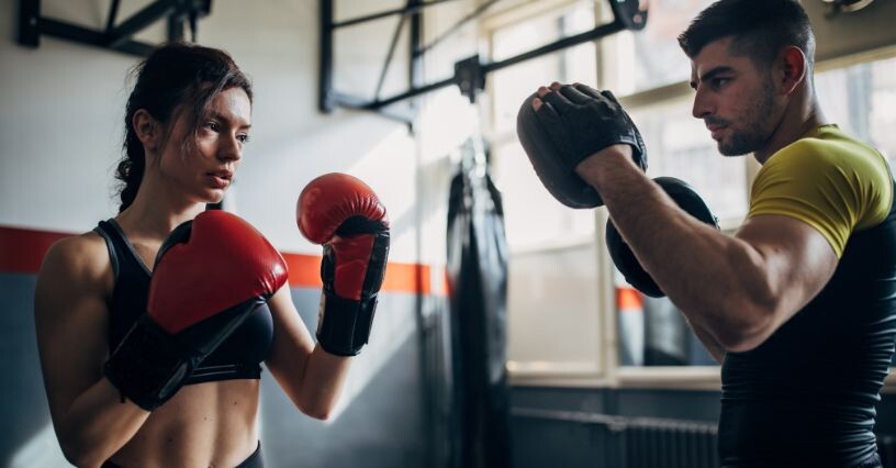 Dvojica trénuje s boxerskými rukavicami v posilňovni