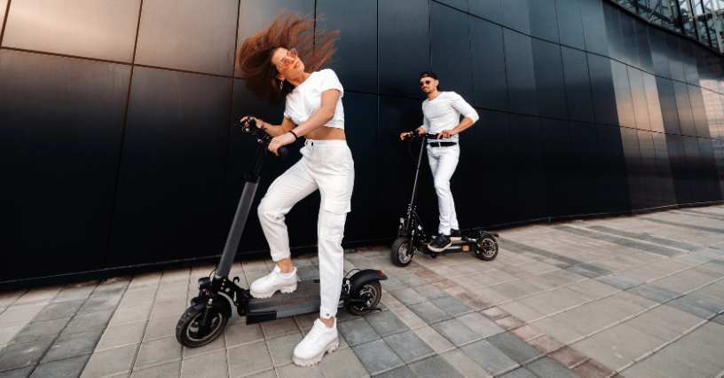Dvaja ľudia jazdia na elektrických kolobežkách pred modernou budovou