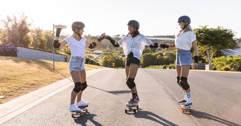 Traja ľudia jazdia na skateboarde na ceste a navzájom sa podporujú