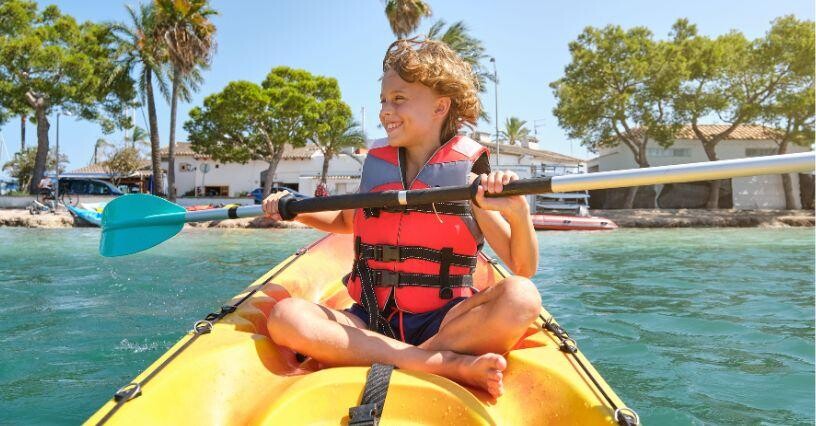 Dieťa na kajaku vesluje na vodnej ploche