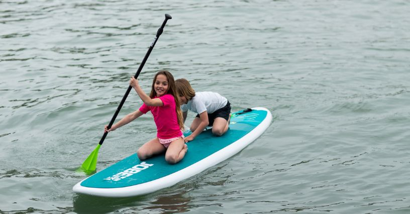 Dvaja mladí ľudia sa bavia na paddleboarde na vode